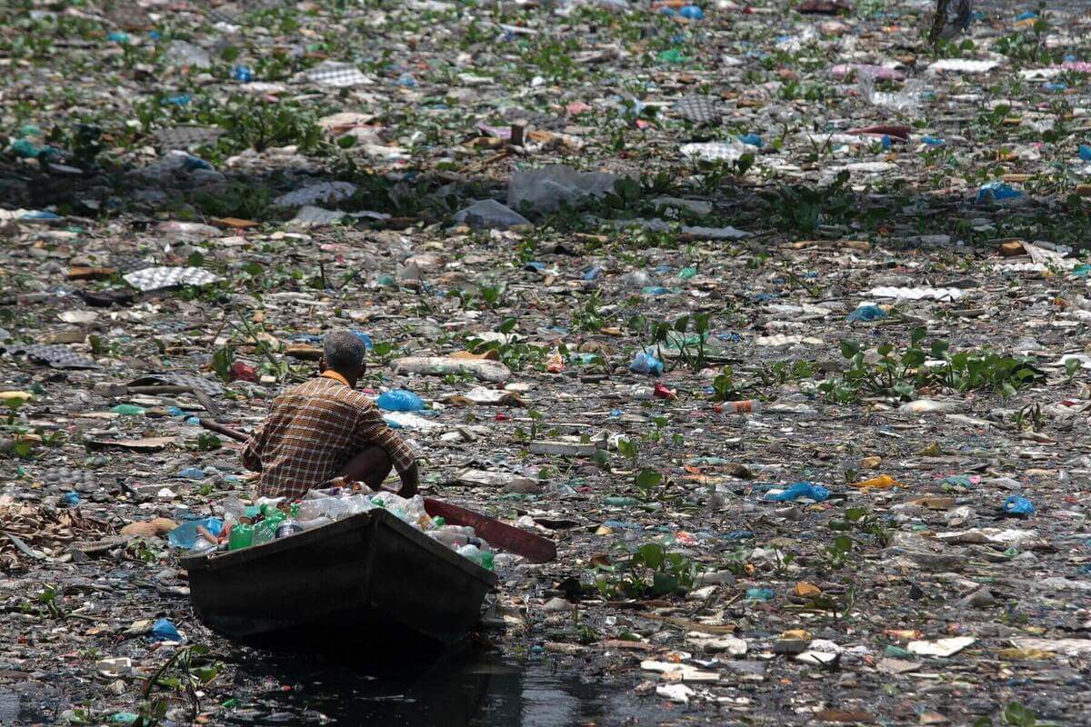 Most Polluted Rivers A Man rowing boat through river full of various waste